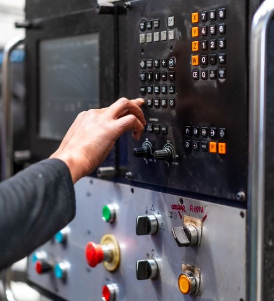 Unrecognizable operator touching the panel of a numerically controlled metal industrial factory machine
